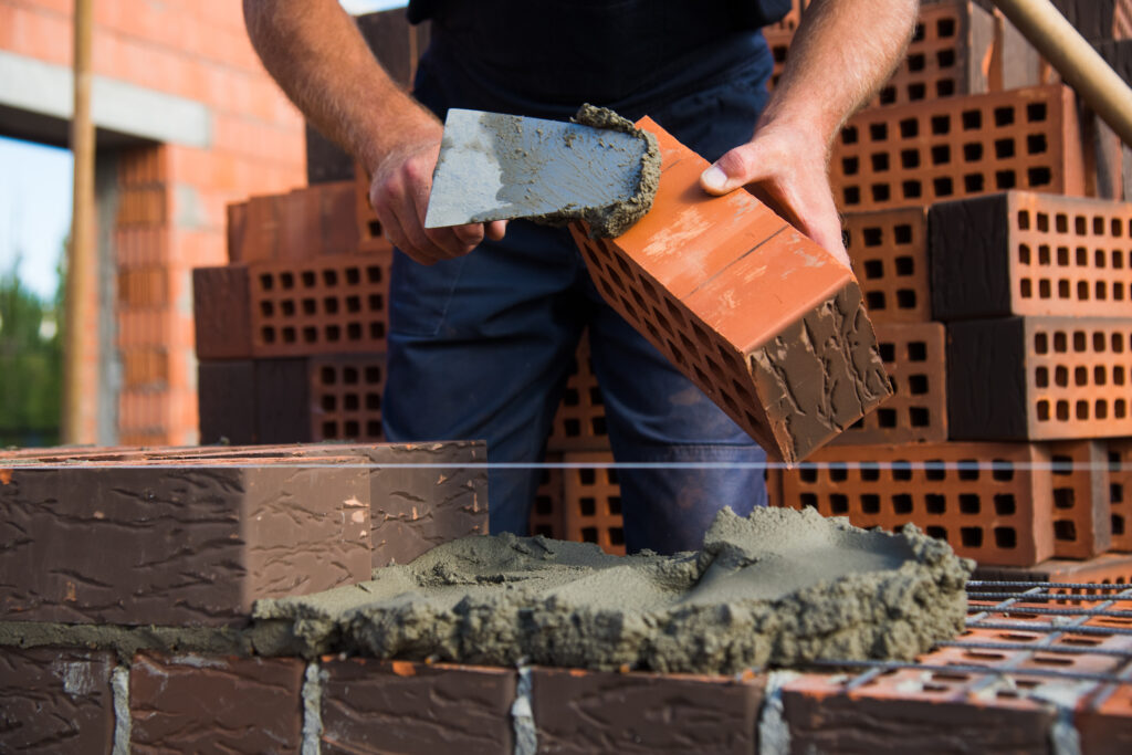 Bricklayer,Worker,Installing,Brick,Masonry,On,Exterior,Wall.,Professional,Construction