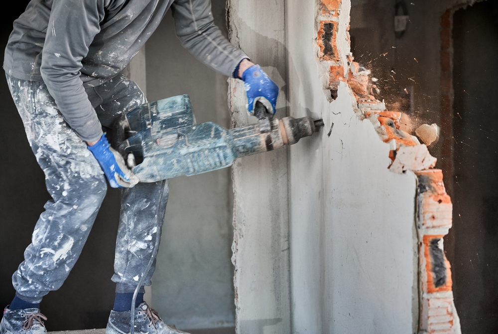 Close,Up,Of,Man,Builder,In,Workwear,Drilling,Wall,With
