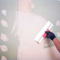Hand,With,A,Spatula.,Worker,Trowels,Putty,On,Drywall,With