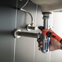 Plumber,Uses,Wrench,To,Repair,Water,Pipe,Under,Sink,There